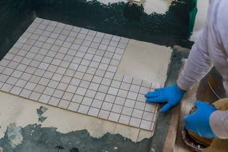Troweling mortar a concrete floor in preparation for laying floor ceramic tiles